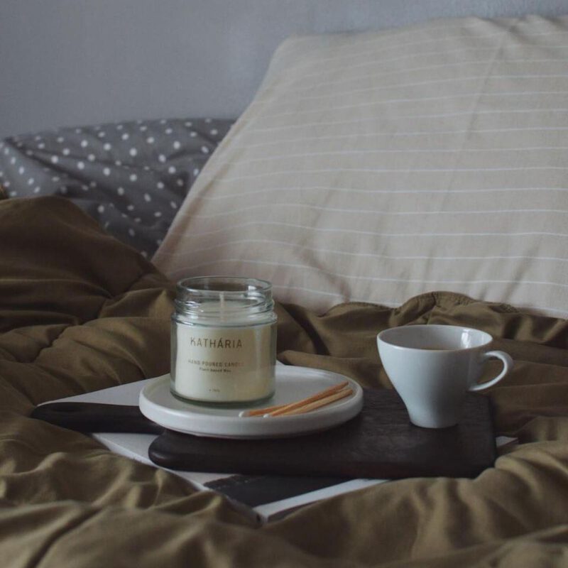 Foto af en seng med bakke, herpå duflys i glas og kaffekop